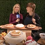 woman interviewing chef standing in front of baked pies